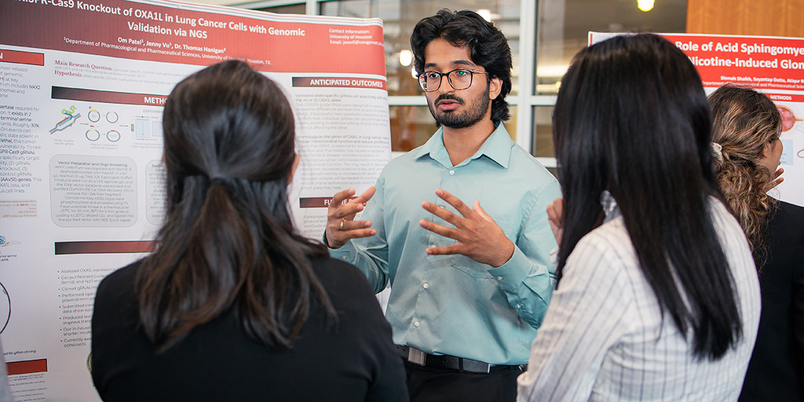 Researcher presents poster to symposium attendants